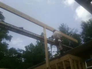Carpenter setting a ridge beam over a new addition frame — Ice Dam Removal by Roofing Brothers in Highland Park
