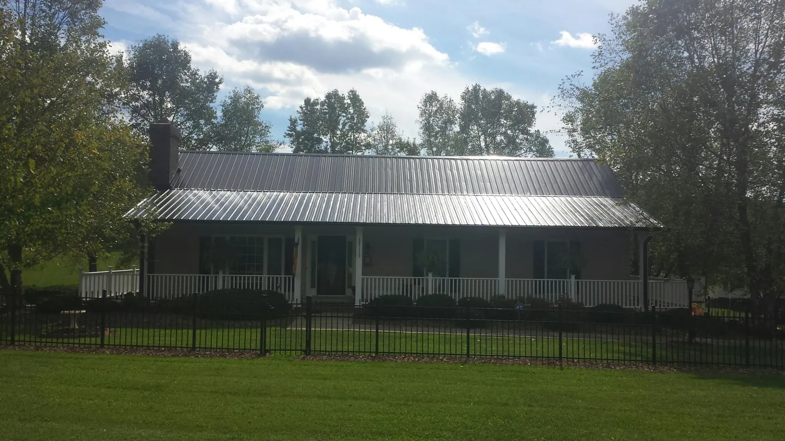 Gray metal roof on a brick ranch with a full width front porch — Gutter Guard Installation work by our crew in Highland Park